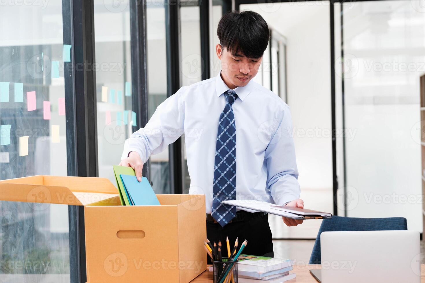 A man in a suit is opening a cardboard box on a desk photo