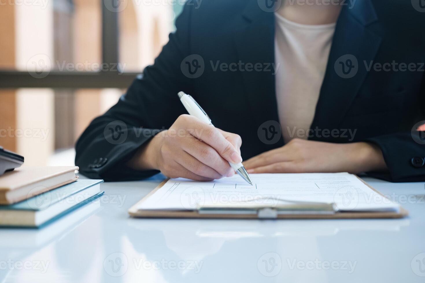 A woman in a suit is writing with a pen on a piece of paper photo