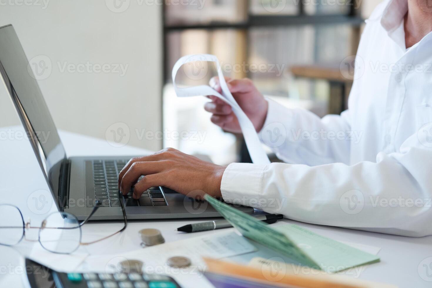 Accountant filling in items from a bill and use computers to calculate financial budgets photo