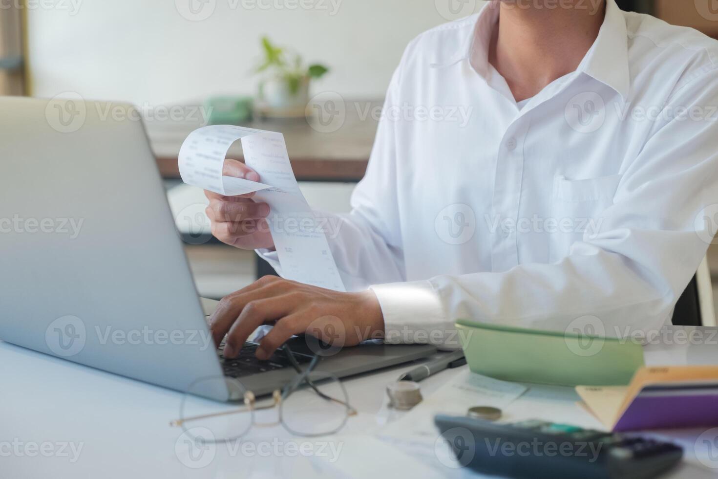 Accountant filling in items from a bill and use computers to calculate financial budgets photo