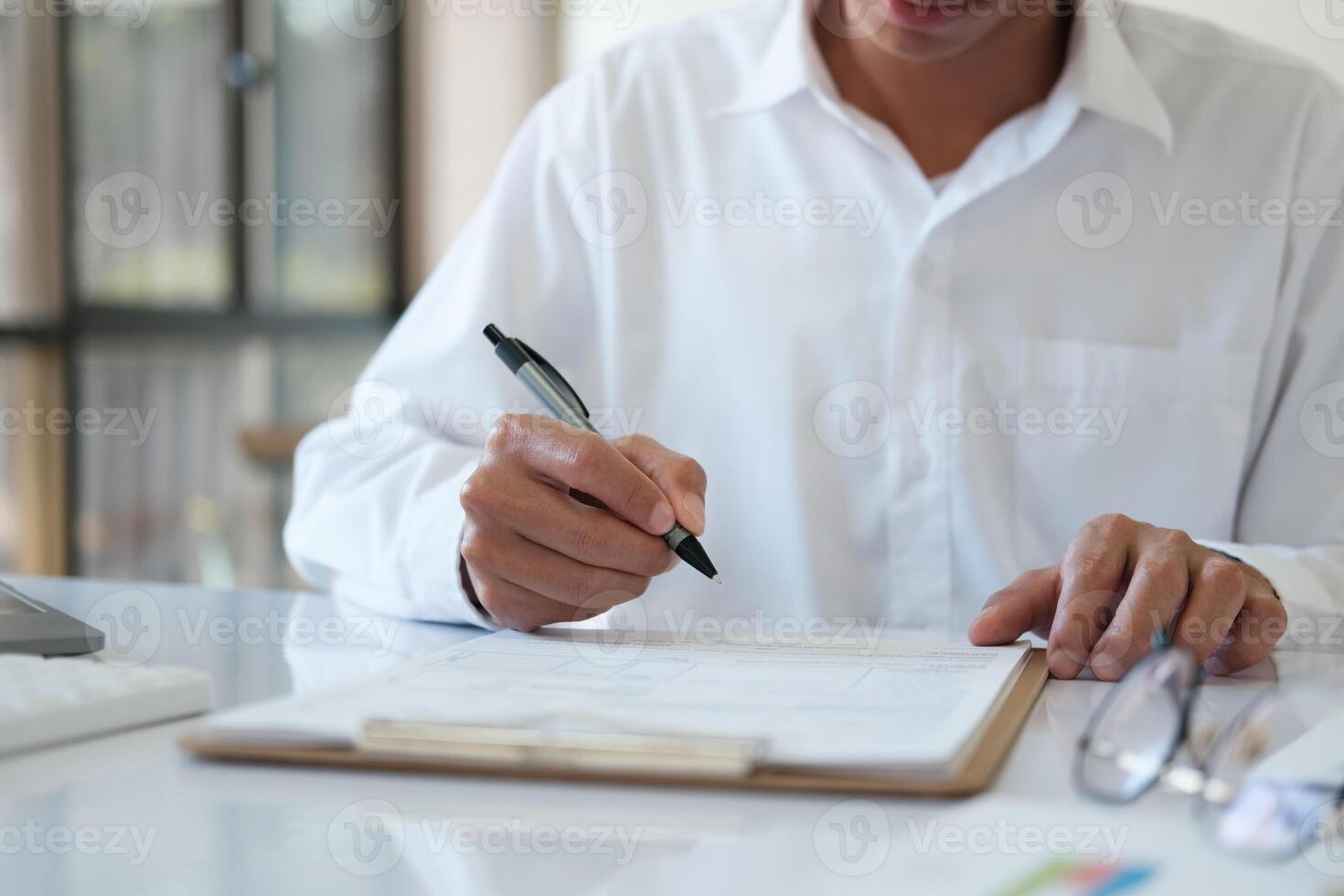 A man is writing on a piece of paper with a pen photo