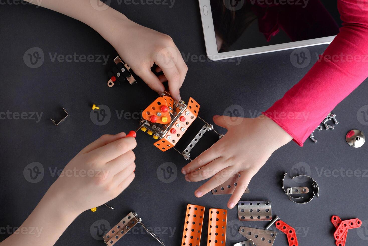 Children piece together robot from small metal parts and screws. Highlighting learning, teamwork, creativity, and interactive engagement photo