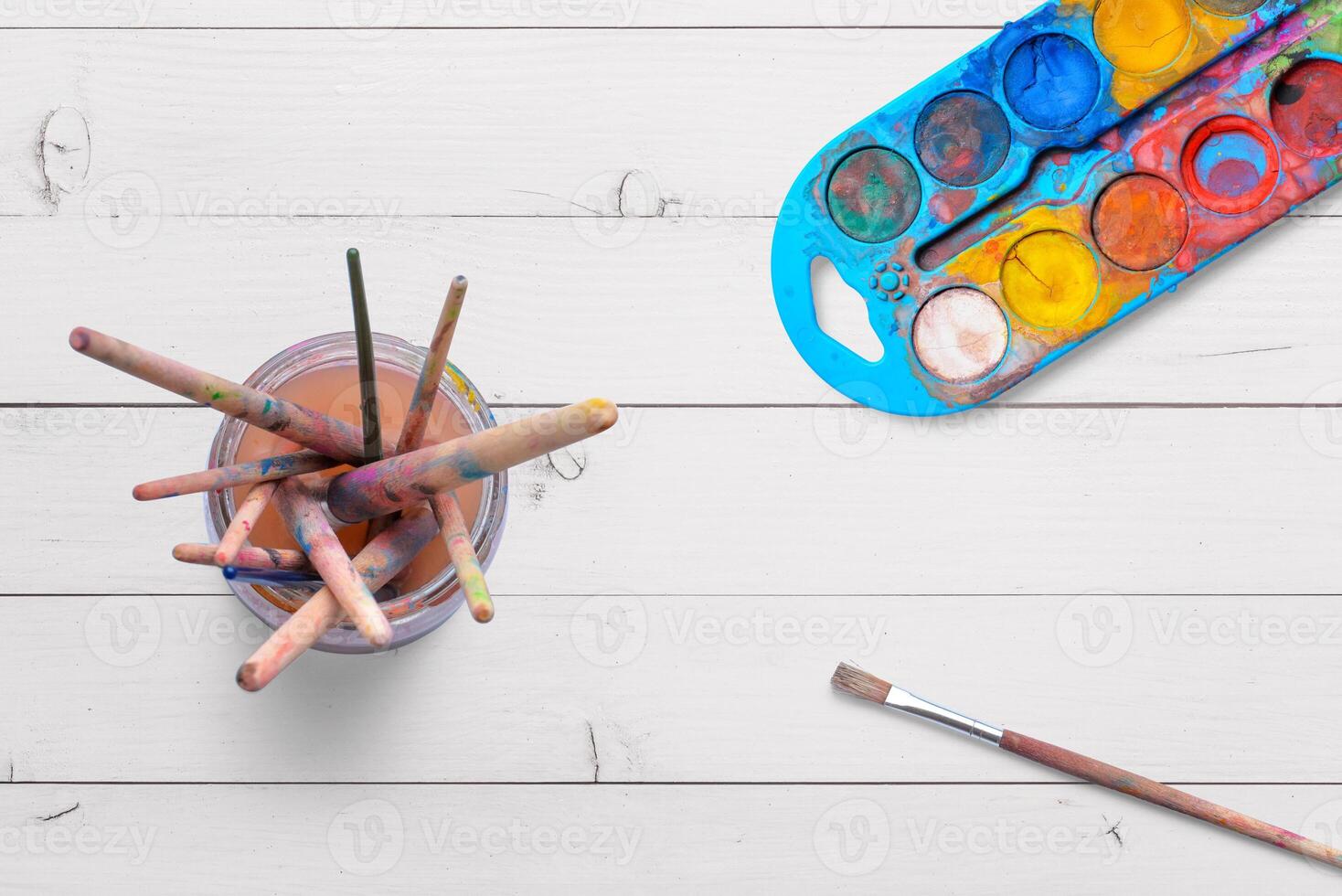 Top view of water crayons and paint brushes in a jar with paint. Ideal for artistic concepts, painting supplies, or creativity themes photo