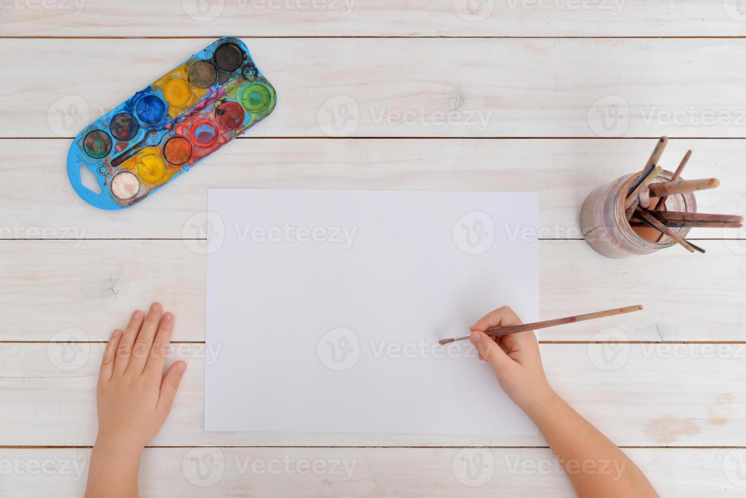 Hands use brush for watercolor painting on clean paper. Concept of creativity, art, childhood, imagination, and artistic expression photo