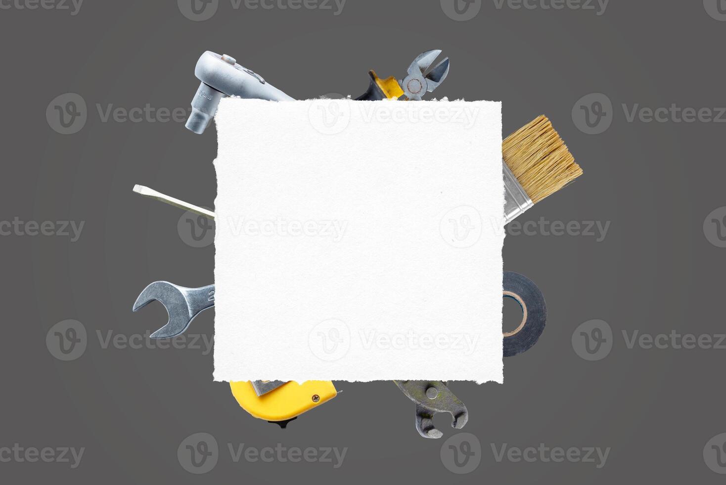 Clean paper surrounded by tools, brush, pliers, screwdriver, tape measure, adhesive tape, wrench. Ideal for text, logo promotion. Top view, flat lay composition. DIY concept photo