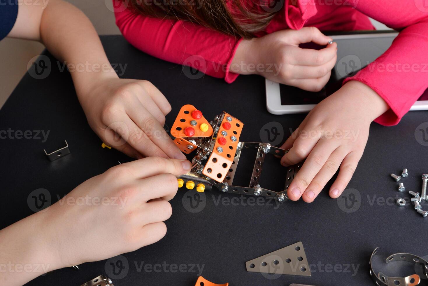 Children assemble robot, showcasing engineering skills. Top-down view of table. Concept of education, creativity, and hands-on learning photo