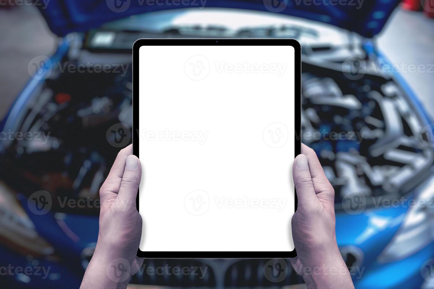 Serviceman holds a tablet in front of a car with an open engine compartment. Isolated display for service promotion, applications, parts sales photo