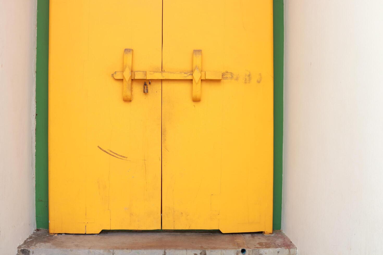 Bright yellow painted antique wood door lock on closed wood door in white cement frame of building in Wat Pho, Bangkok in Thailand. photo