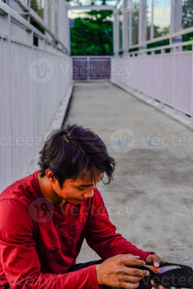 el hombre en rojo es mirando a el contenido de el billetera. foto