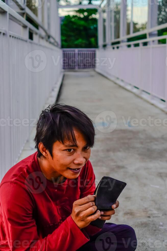 the man in red is looking at the contents of the wallet. photo