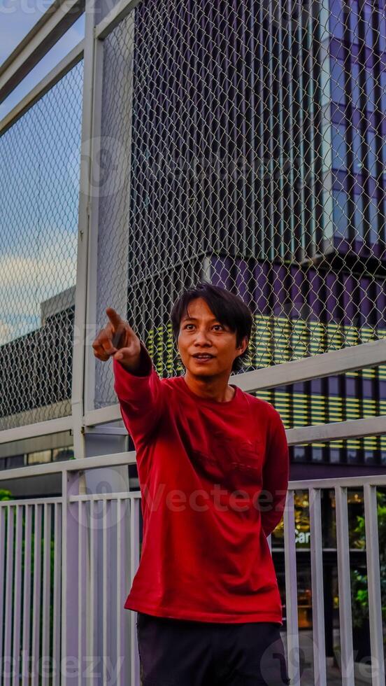 Javanese man in red is pointing at something. photo