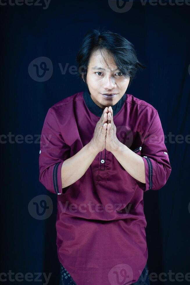 front view of a man in Muslim attire giving a sign of respect on a black background photo