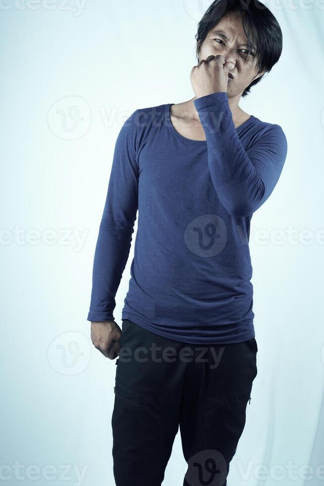 Portrait of frustrated man pinching nose with disgust on his face because of bad smell, isolated on white background. photo