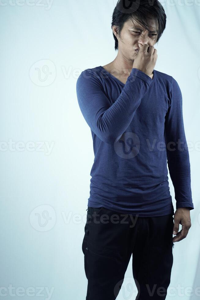 Portrait of frustrated man pinching nose with disgust on his face because of bad smell, isolated on white background. photo