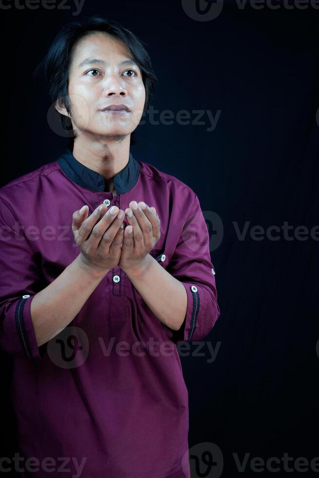 front view of a man raising his hands in prayer on a black background. photo