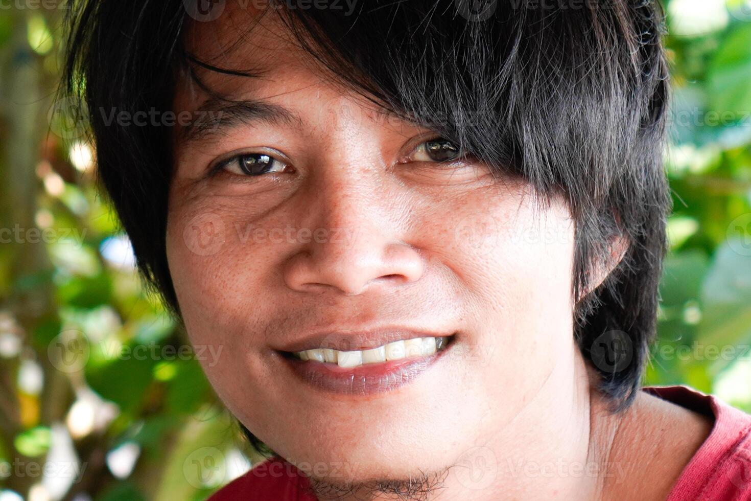 a close-up of the face of a Javanese man who appears to have long hair. photo