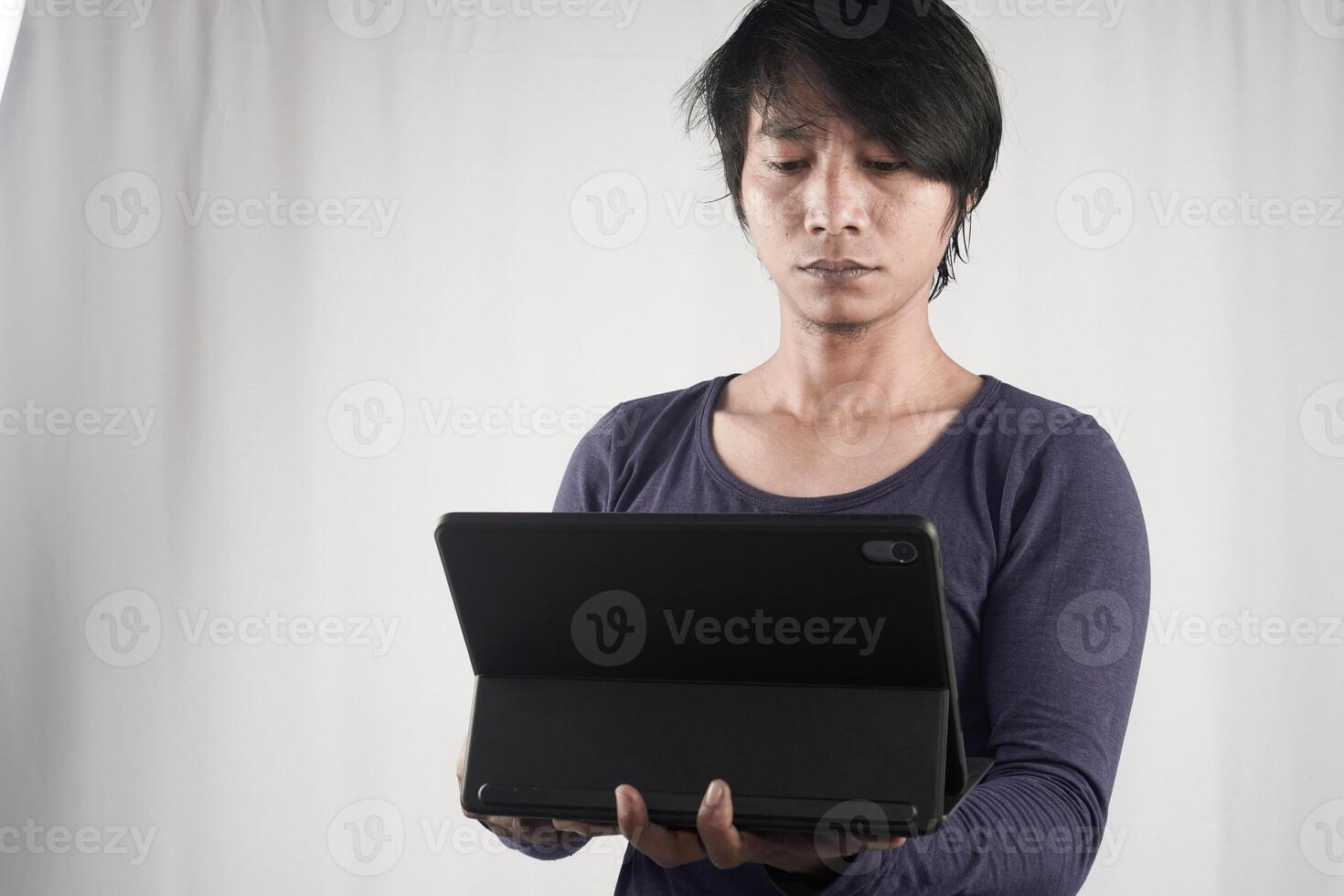 Portrait of young Asian man standing and holding laptop computer notebook on technology device isolated on white background. Lifestyle of business people. photo
