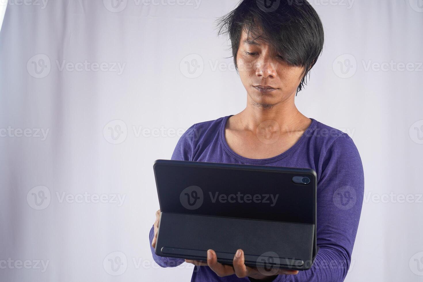 Portrait of young Asian man standing and holding laptop computer notebook on technology device isolated on white background. Lifestyle of business people. photo