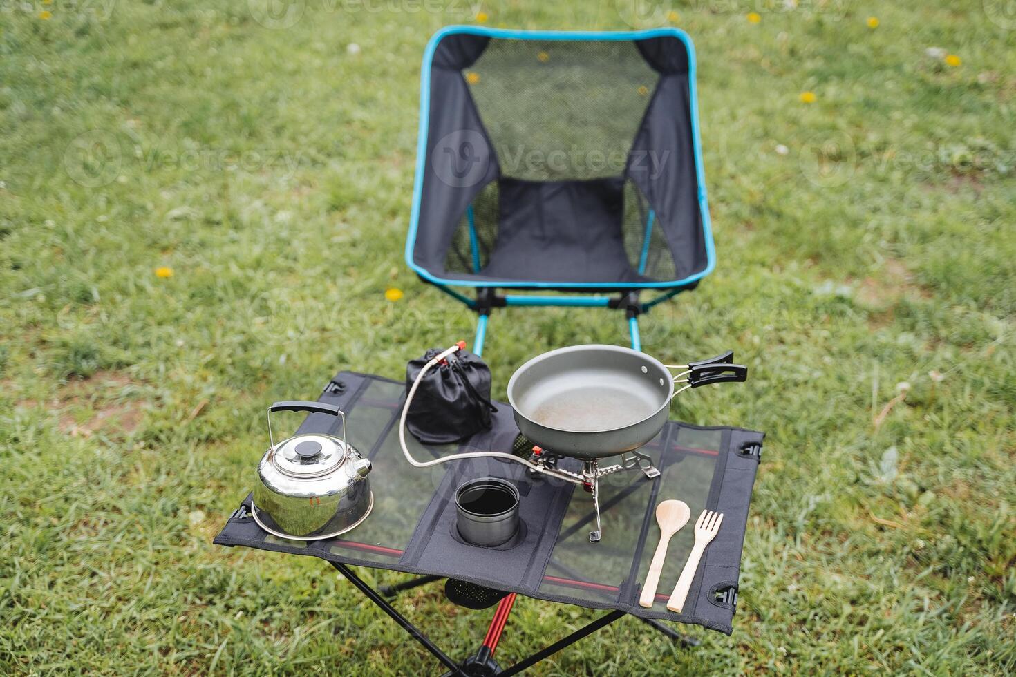 Camping furniture for outdoor recreation, folding chair, tourist utensils for eating, compact table, burner with cylinder, frying pan with handles. photo