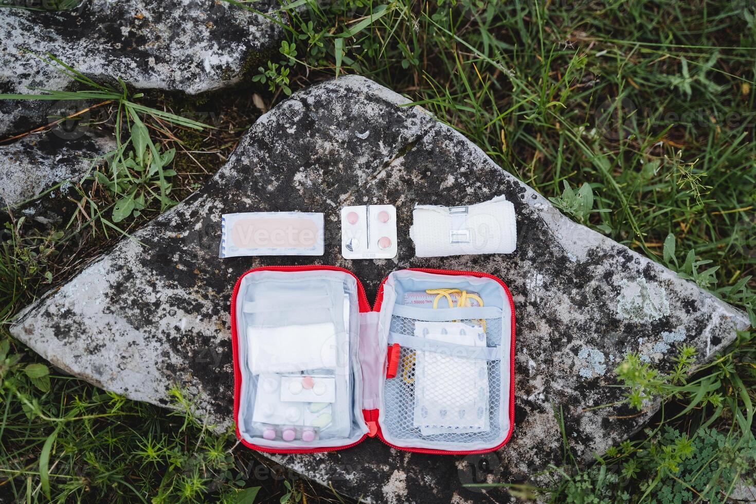 The layout of the first aid kit on the stone, the view from above the pills for pain, a set of medicines on a hike, tourist safety on trekking in the mountains. photo