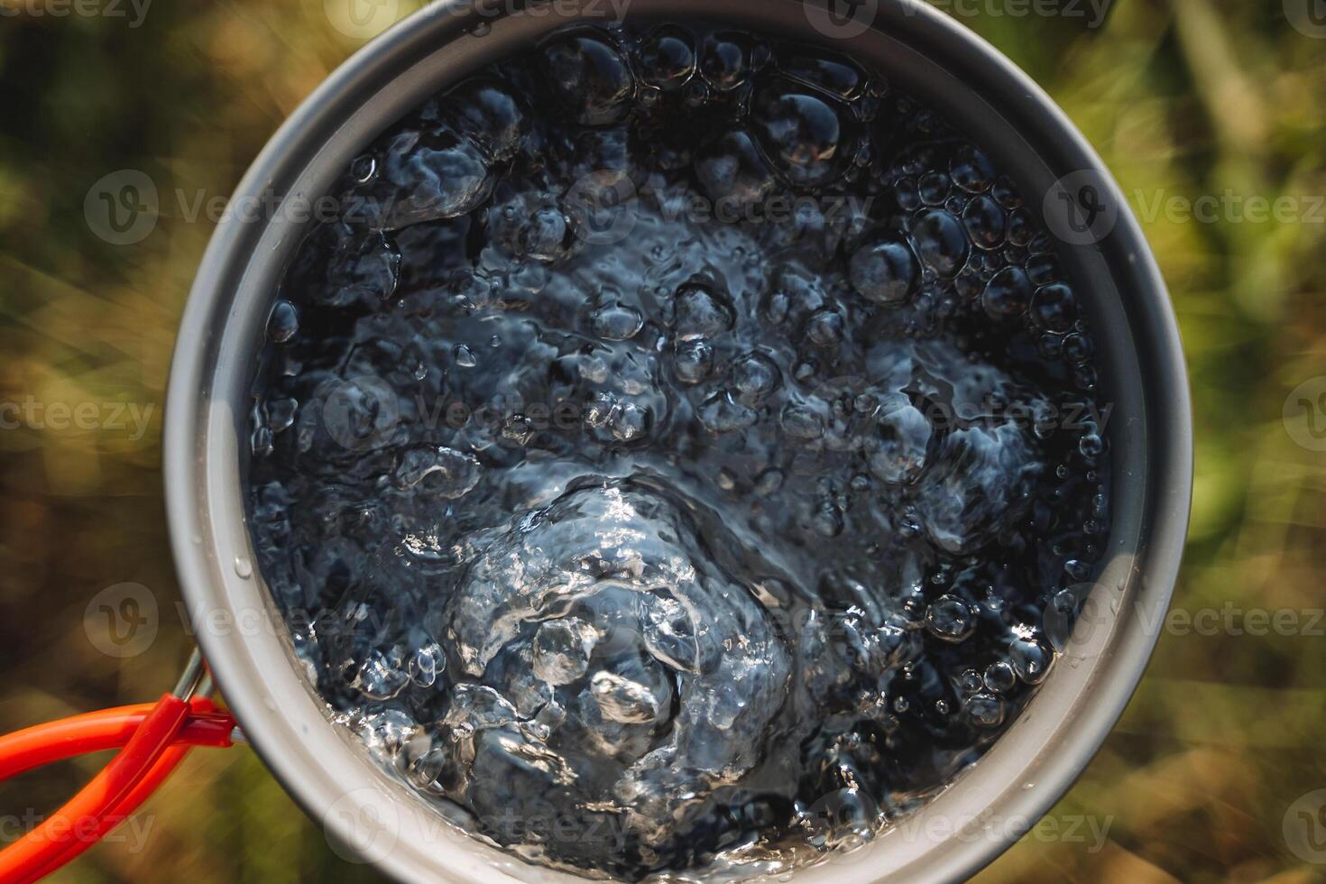 Boiling water top view, tourist utensils, warming water in a pot, a pot for hot drinks, air bubbles, bubbling liquid. photo