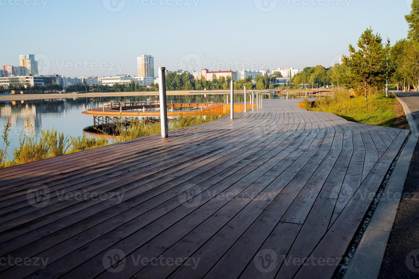 A road of boards, a wooden platform, a pedestrian path, a park in the city by the lake, a river embankment, a landscaped area, a place to relax. photo