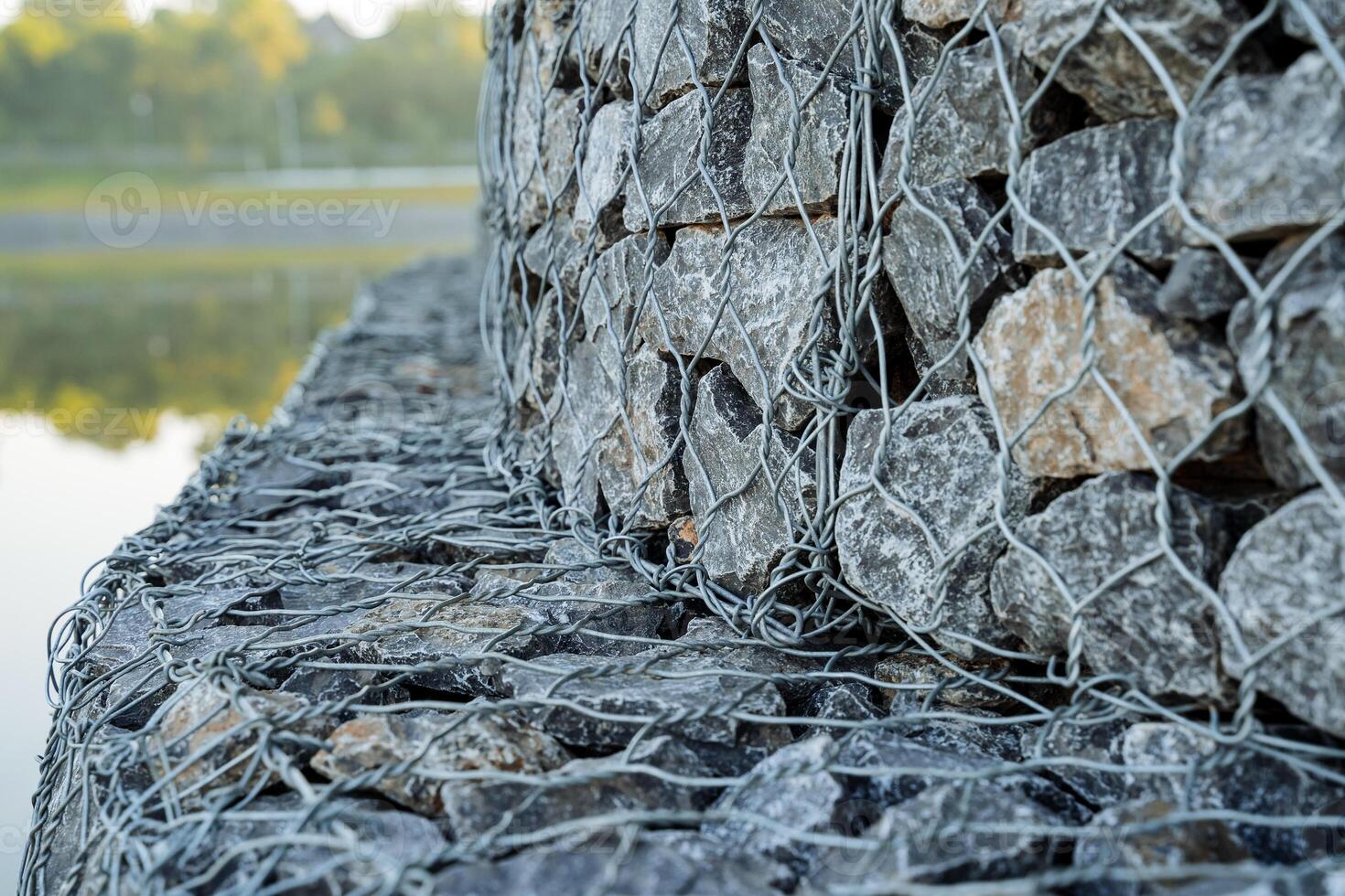Flood protection, strengthening the river bank with stones, a barrier, the technology of assembling stones in a heap, rabitz mesh. photo