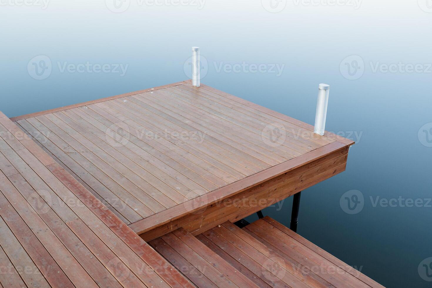A wooden pier on the sea, a place for mooring boats, a platform of boards on the reservoir, a pier made of wood, the water surface, the sea shore, a quiet harbor. photo