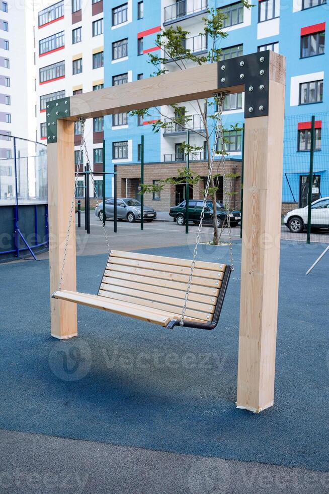Street swings hang in the courtyard of the house, a children's playground on the street, wooden swings on chains, a residential quarter a place of rest for citizens. photo