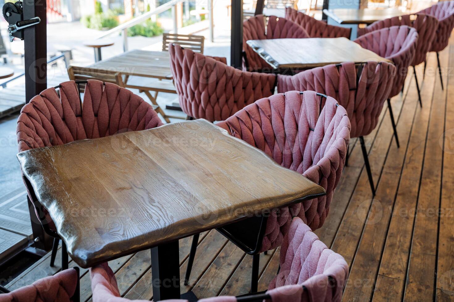 Beautiful interior of an outdoor cafe, wooden table, soft chairs of pink color, an open-air restaurant, a place for lunch of citizens photo