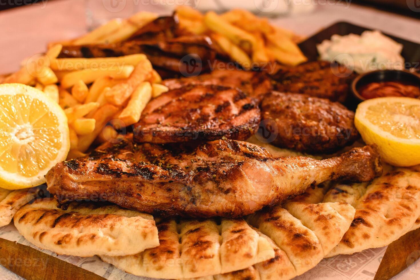 Mix Grill Includes chicken leg, pancetta, sausage, bacon, burger, potatoes, sliced pita served with lemon and sauce in greek tavern. Selective soft focus. Mediterranean cuisine photo