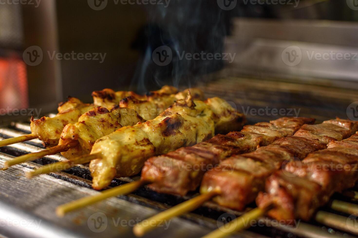 Close-up of cooking mouthwatering pork and chicken souvlaki roasting on a BBQ grill in greek tavern. Selective soft focus. Mediterranean cuisine photo