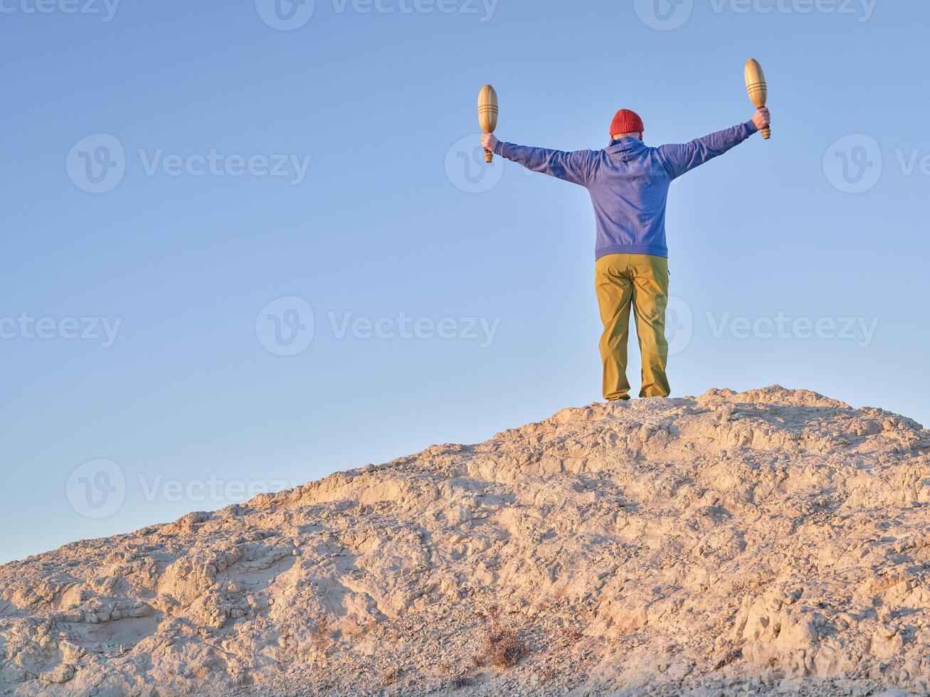 senior man is exercising with wooden Indian clubs outdoors photo