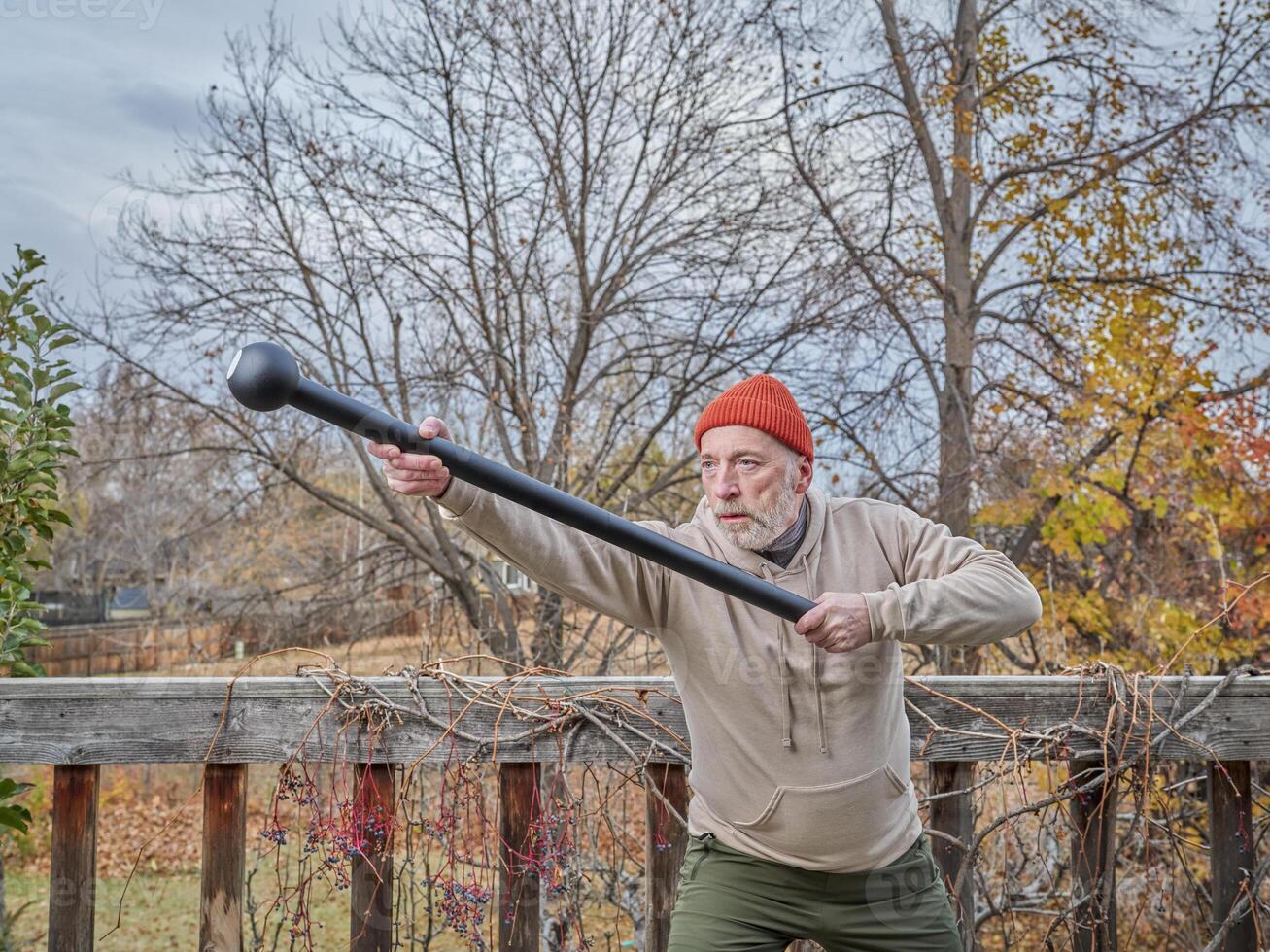 senior man is exercising with a steel mace photo