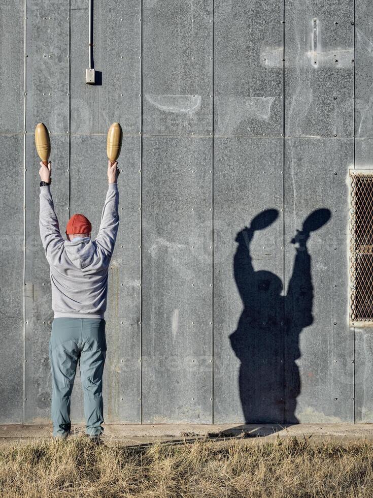 senior athletic male is exercising with wooden Indian clubs photo