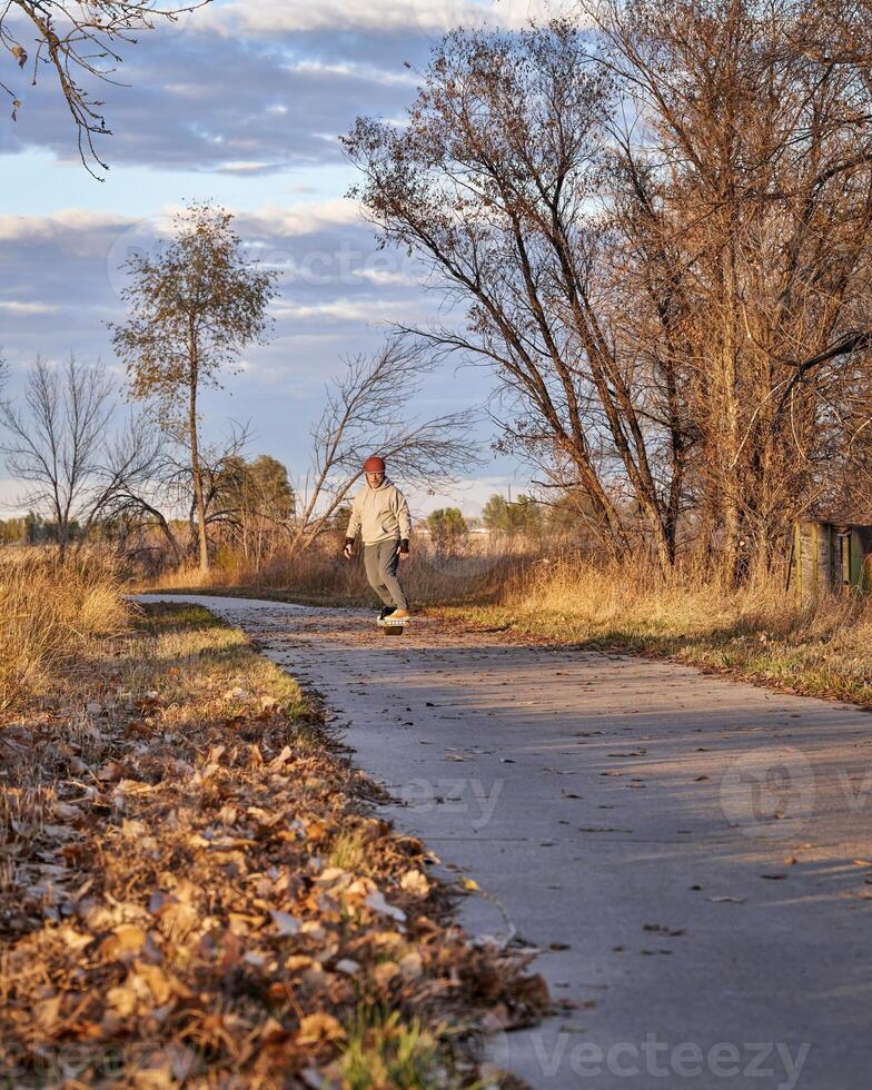 senior man is riding one-wheeled electric skateboard photo