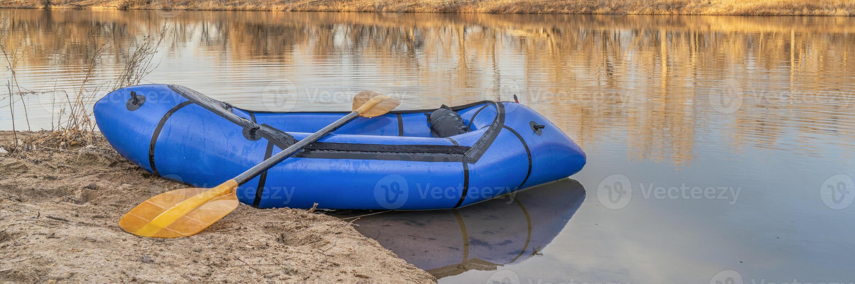 inflatable packraft with paddle on a lake shore photo