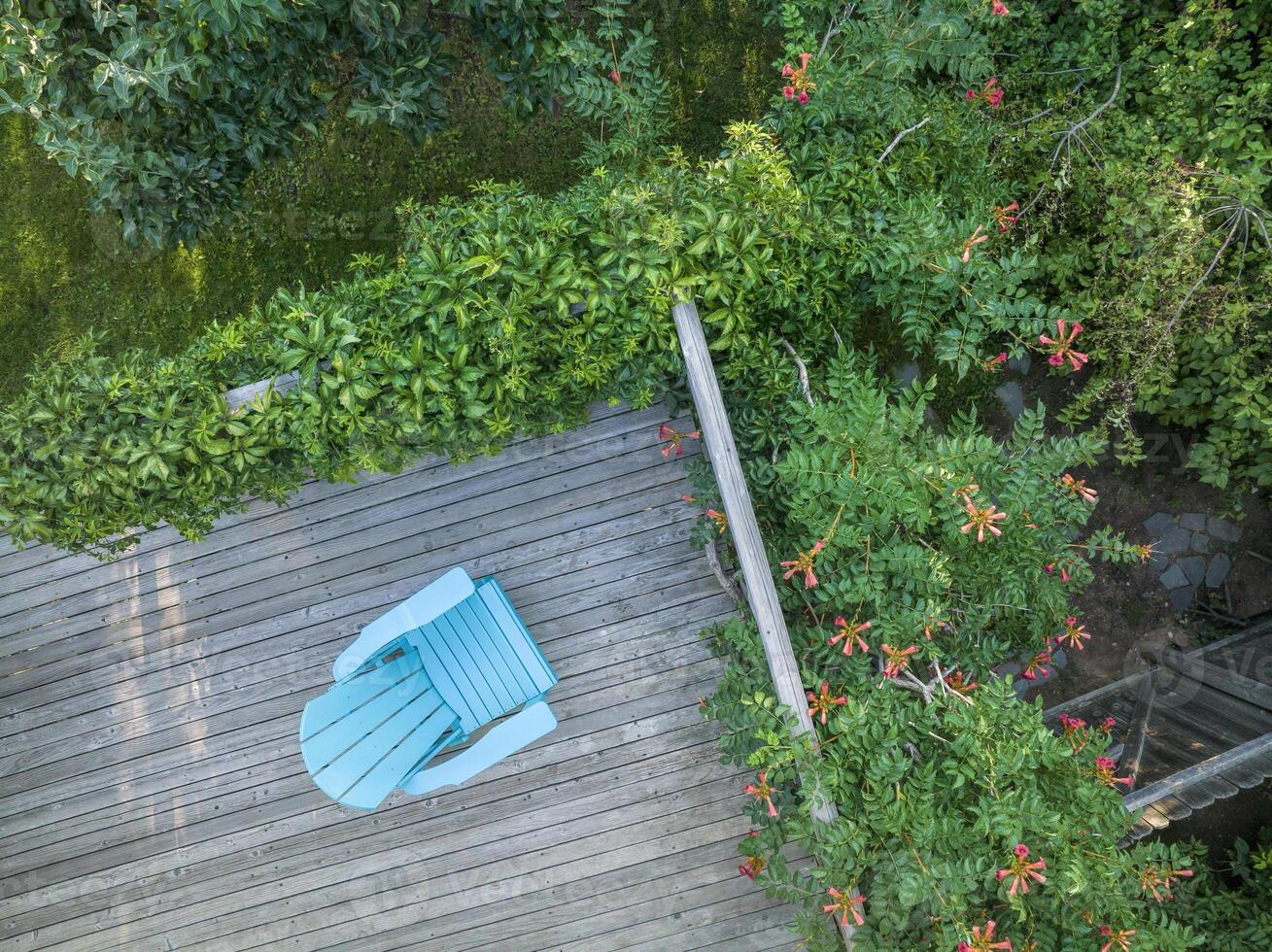 empty Adirondack chair on a wooden backyard deck photo