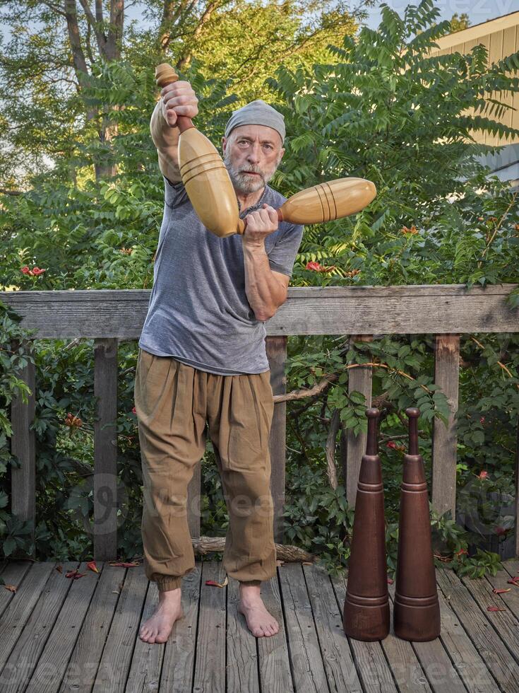 senior man exercising with Indian clubs and Persian meels photo