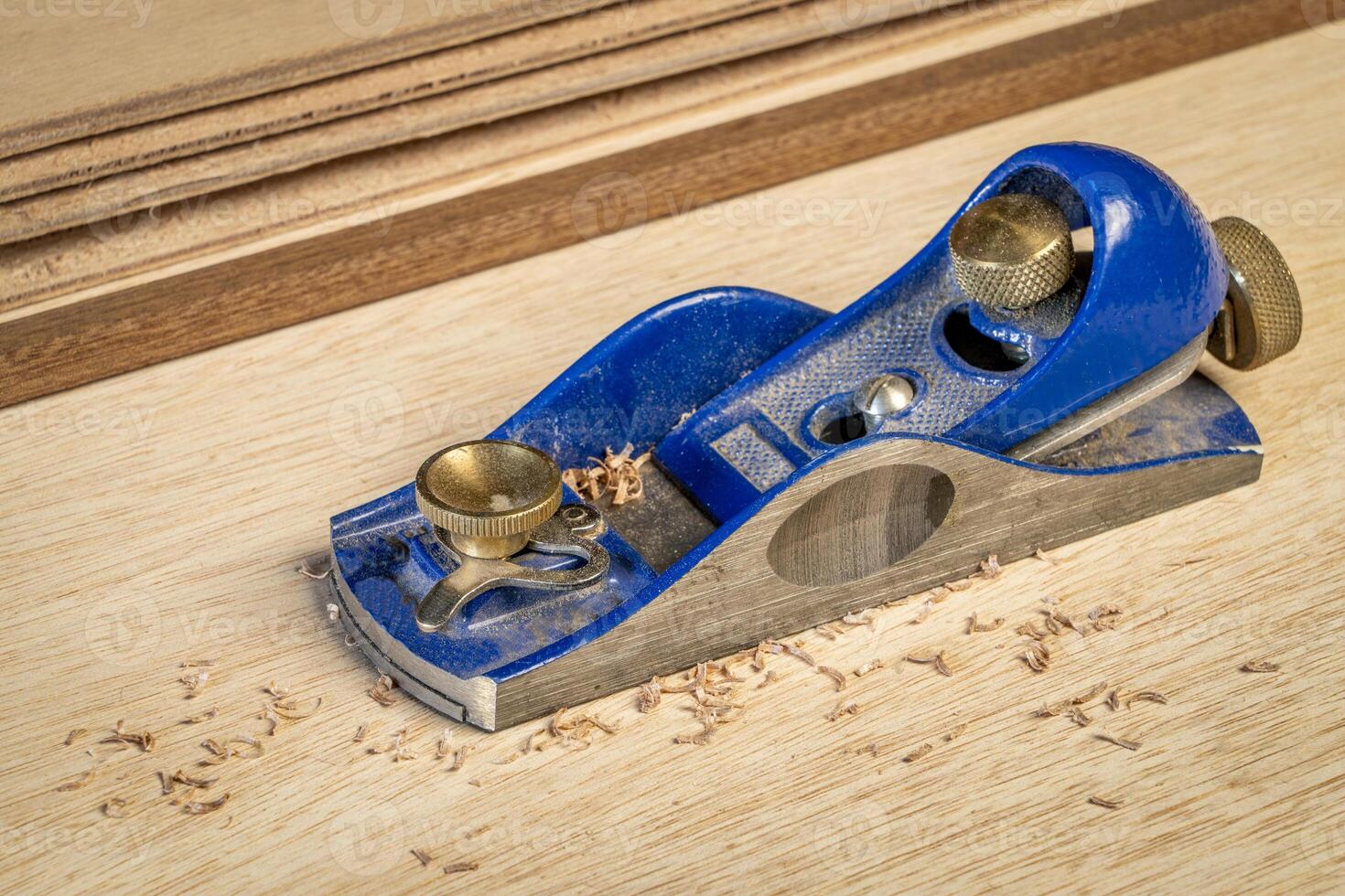 dusty hand block planer against okoume plywood background with some shavings - woodworking concept photo