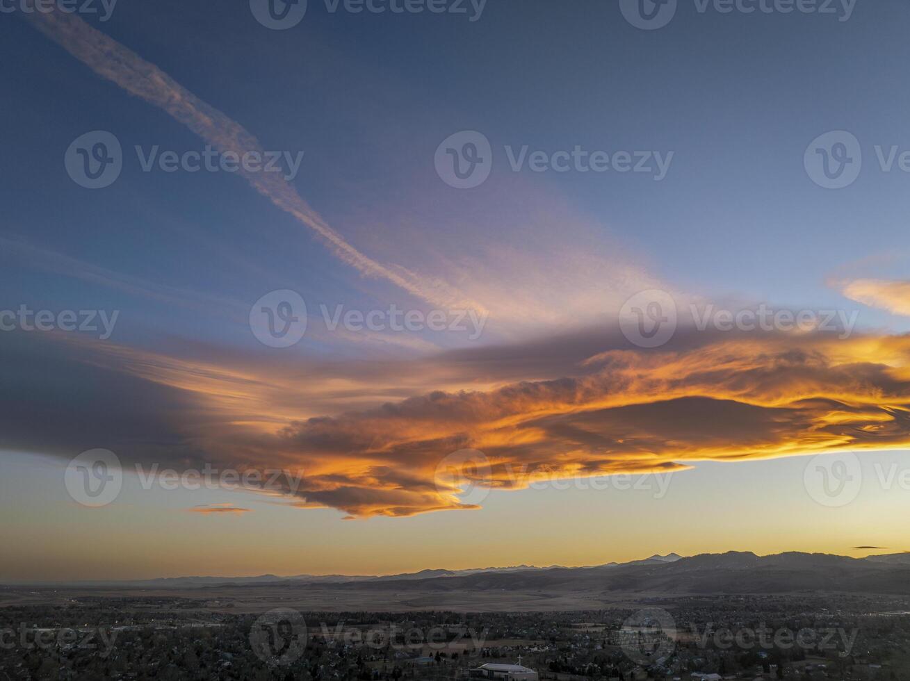 clouds and contrails over Rocky Mountains foothills and city of Fort Collins, Colorado, in sunrise light photo