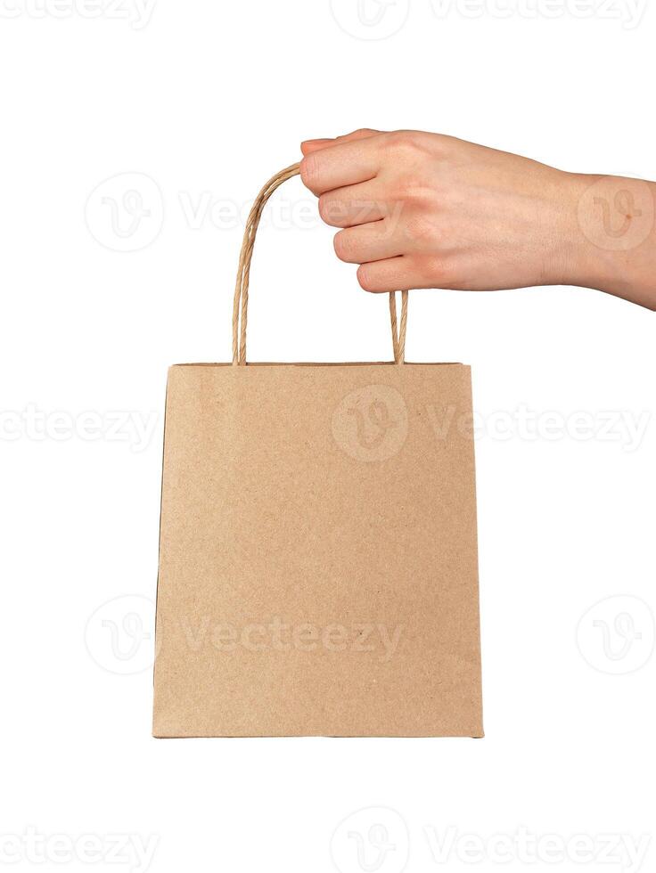 Hand holding, giving, presenting small gift bag, kraft package isolated on white photo
