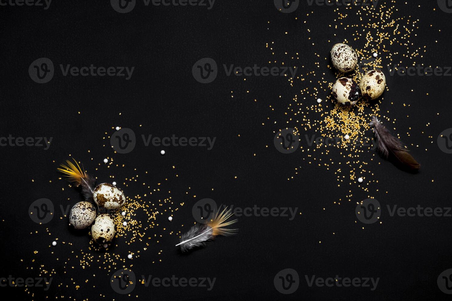 Moody easter background. Quail eggs, feathers and golden sugar sprinkles on black background. Happy easter holiday photo