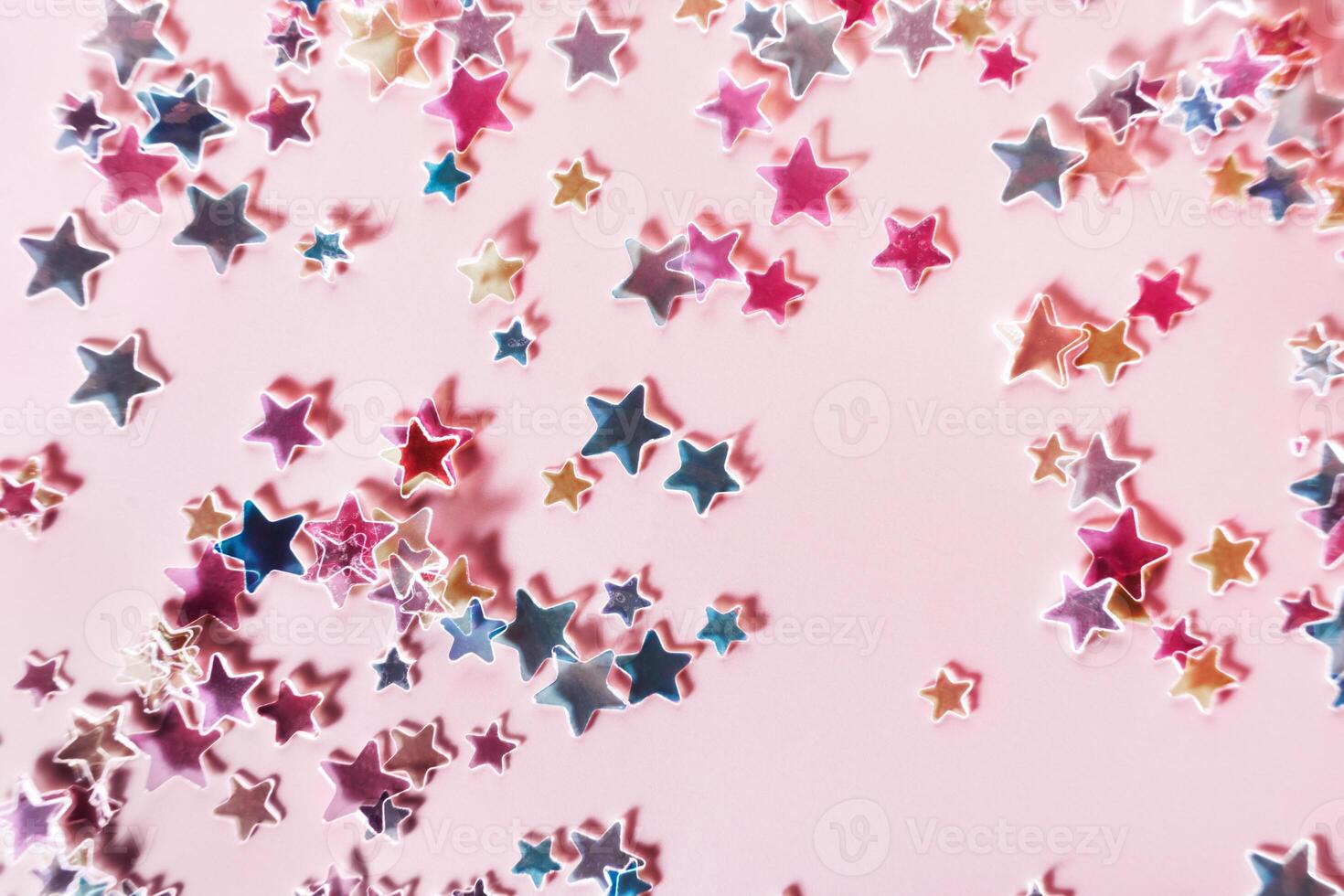 Multicolor holographic Stars Glitter Confetti on pink background. Festive backdrop, selective focus photo