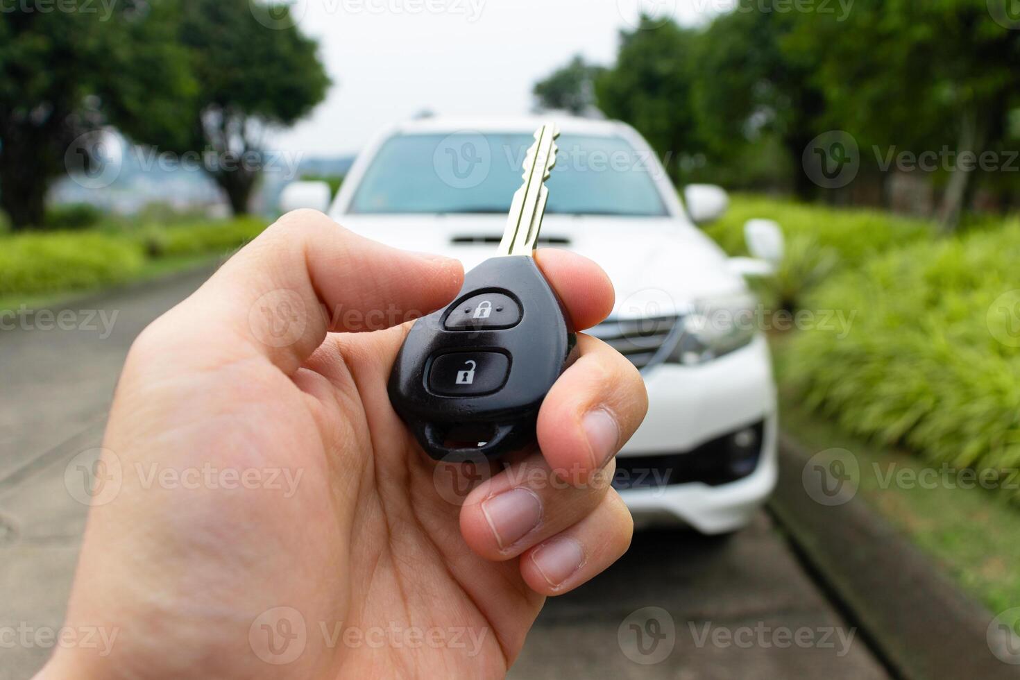 Car key in hand with car on the background. Car stuff concept. After some edits. photo