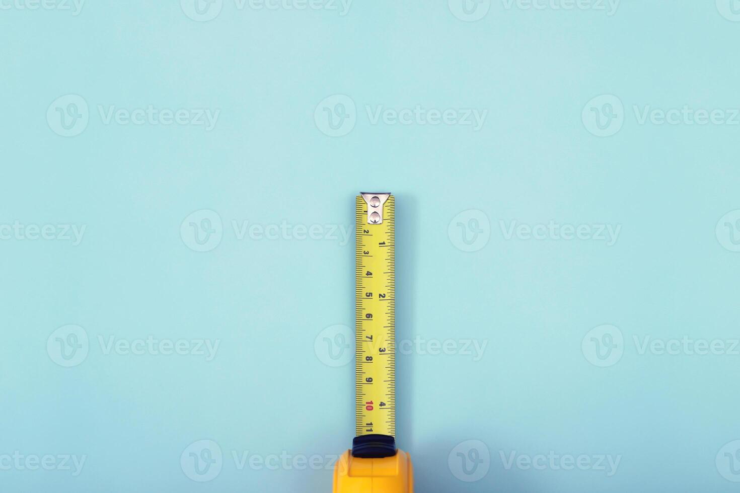 la cinta métrica amarilla para el albañil se coloca sobre un fondo azul. enfoque suave. foto