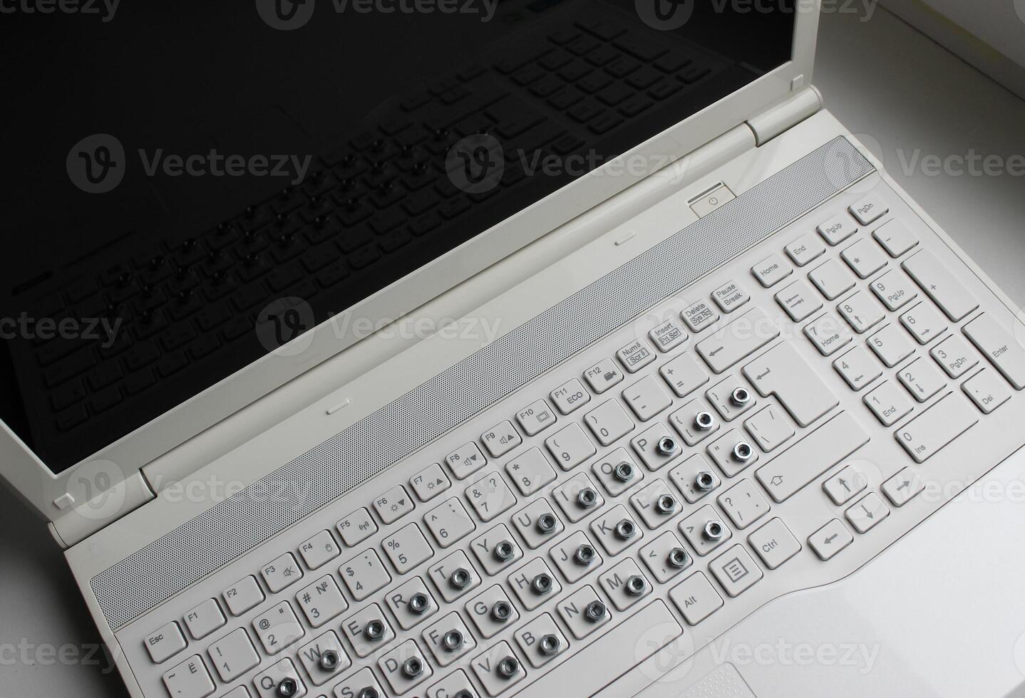 Steel hex nuts on the white keyboard cover a Cyrillic characters top view photo