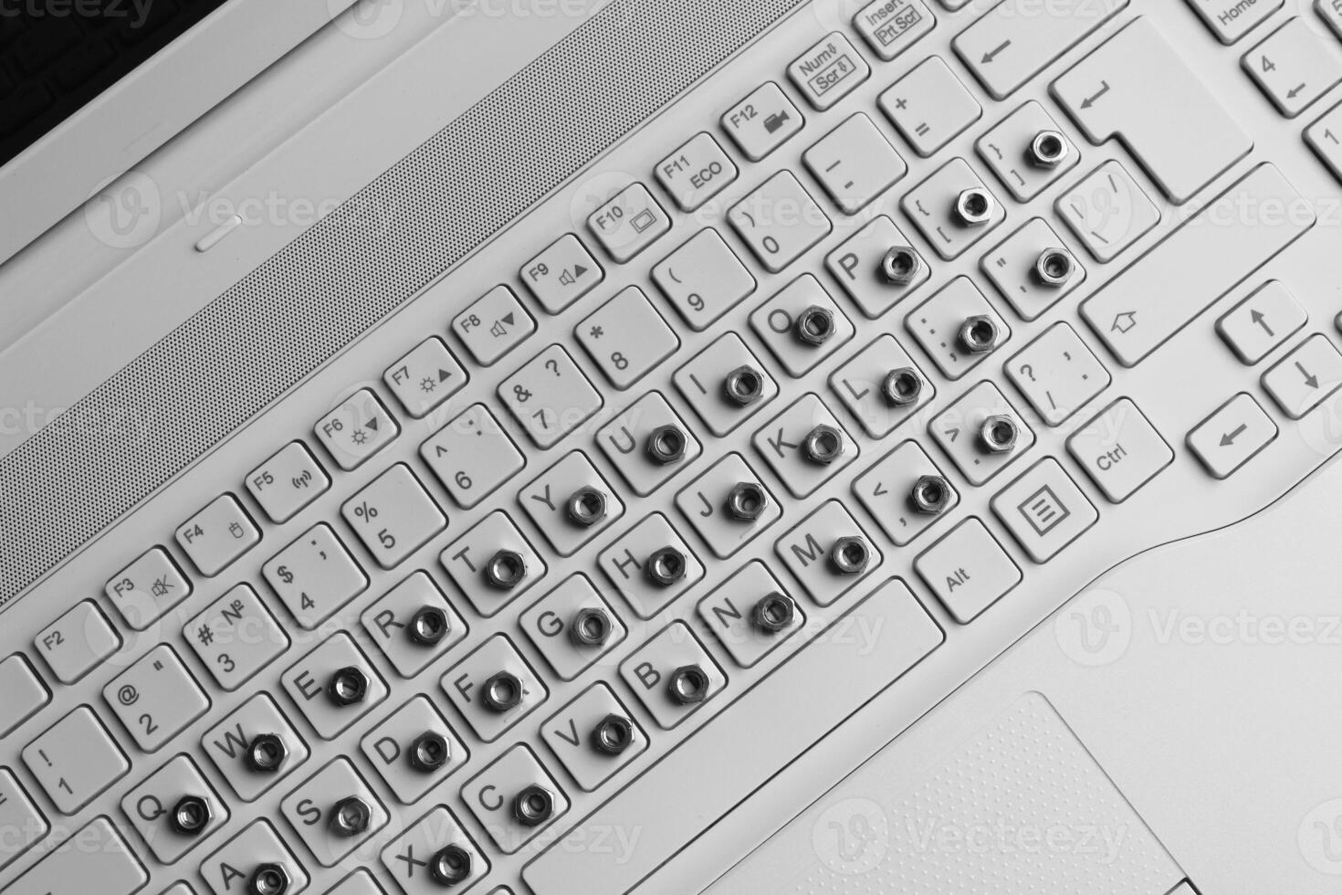 Metal nuts overlap symbols on a white computer keyboard top view stock photo