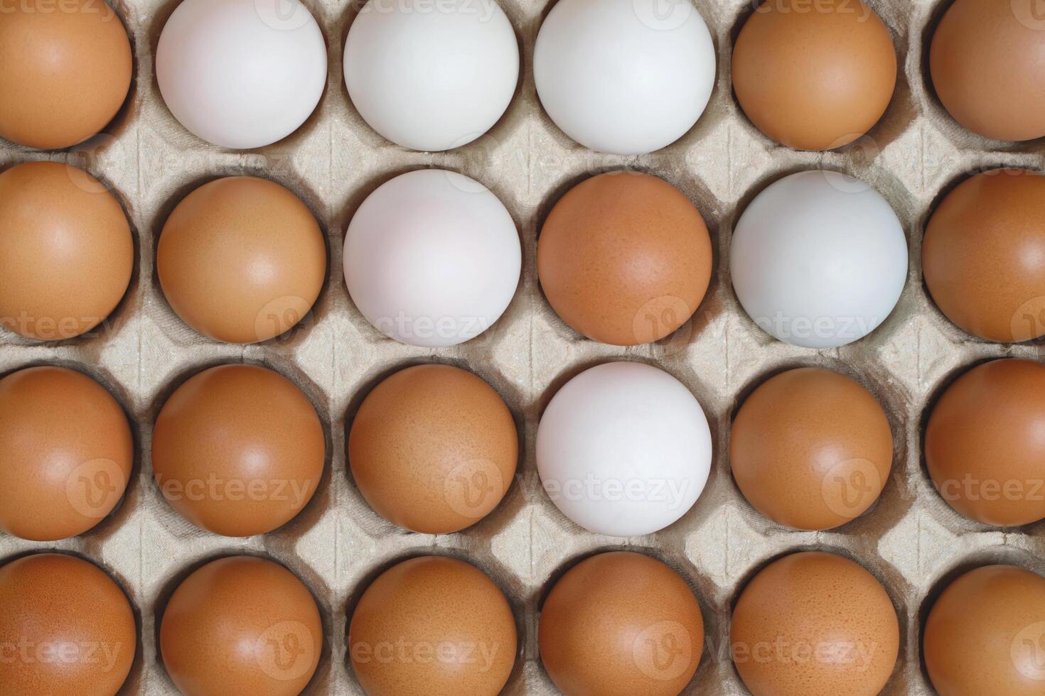 Chicken eggs in a cardboard box ready to cook on a yellow background photo