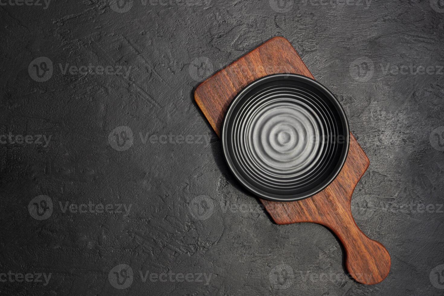 Empty plate with wooden cutting board on black background photo